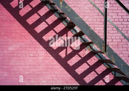 Building exterior with a pink brick wall and metal staircase Stock Photo