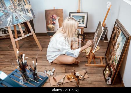 Young, blonde woman painter showing her artwork Stock Photo