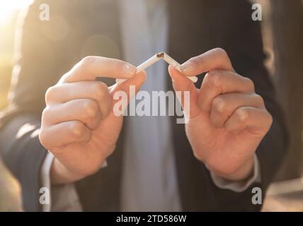 A woman decides to quit smoking and is breaking a cigarette Stock Photo