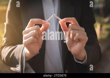 A woman decides to quit smoking and is breaking a cigarette Stock Photo