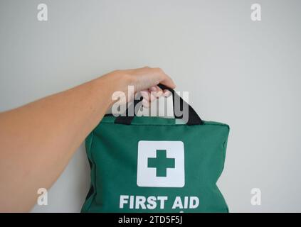 Medical First Aid kit in hand on neutral background. Stock Photo