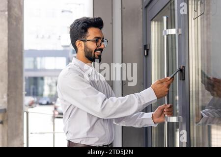 Young businessman using phone to open office door of building, man happy using wireless access, businessman going to work happy smiling. Stock Photo