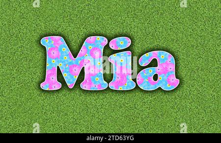 Mia, one of the ten most popular girls' first names in the USA, 2023, written with flowers in baby colours, pink and light blue, on a green background Stock Photo