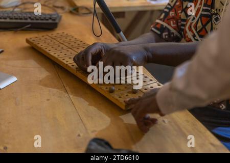Blind African person learning to use the braille number tablet under the guidance of a teacher. Stock Photo