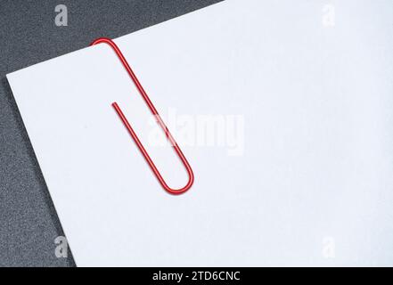 Close up of red paper clip attached to multiple sheets of paper. Stock Photo