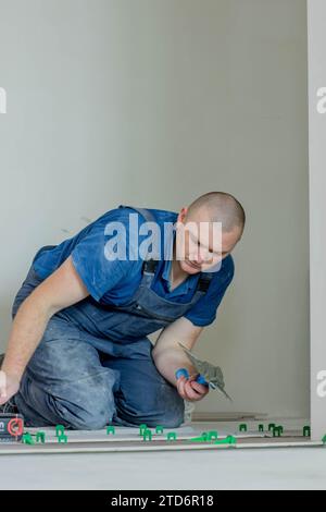 A male construction worker installs a large ceramic tile. Stock Photo