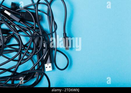 Tangled Black Cables for Modern Gadgets on Blue Background, Copy Space Stock Photo