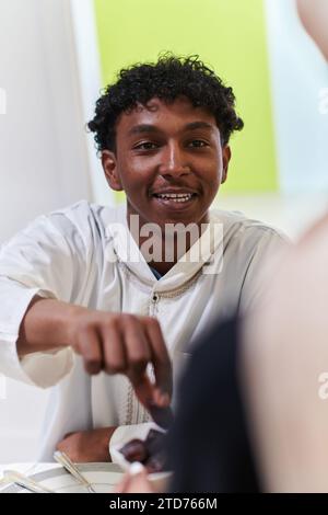 African American Muslim man delicately takes dates to break his fast during the Ramadan month, seated at the family dinner table, embodying a scene of Stock Photo