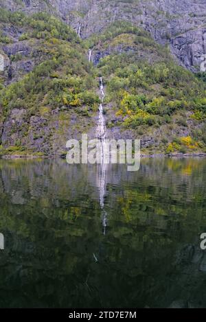 A small waterfalls from the mountain with the reflection in the water. Stock Photo