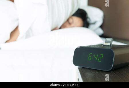 Digital alarm clock blaring but Young woman having trouble with wake up early in the morning. Stock Photo