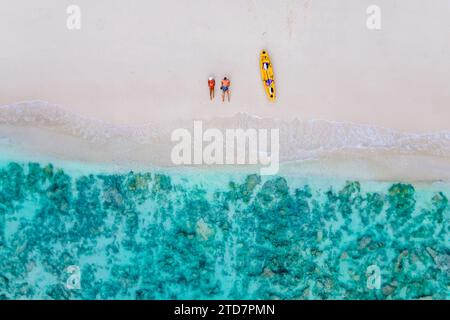 drone view at couple laying down on the beach of Koh Phi Phi Thailand during vacation with a kayak. couple on a beach with a kayak in Thailand at Koh Phi Phi Krabi Stock Photo