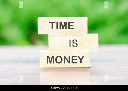 TIME IS MONEY Back to school the inscription on wooden bars against a background of green plants is out of focus Stock Photo