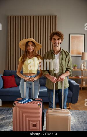 Happy family couple going for trip posing with packed luggage suitcases at home Stock Photo