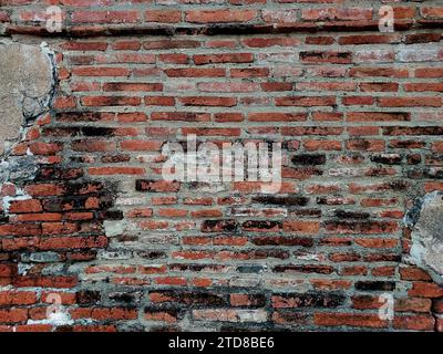 Old weathered brick wall fragment, urban background grunge wall texture Old damaged brick wall with plaster. Stock Photo