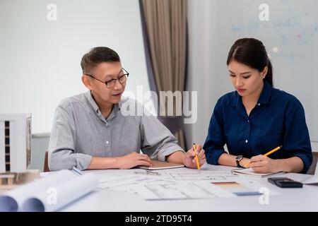 Two architects pointing on blueprint and analyzing about construction of building project together. Stock Photo
