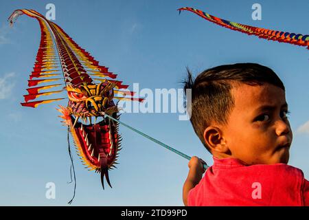 Yogyakarta, Indonesia. 17th Dec, 2023. A boy flies a dragon kite at Parangkusumo beach in Bantul district, Yogyakarta, Indonesia, on Dec. 17, 2023. A dragon kite community in Yogyakarta flied 25 dragon kites on Sunday to attract tourists to visit the Parangkusumo beach for the upcoming Christmas and New Year holiday. Credit: Agung Supriyanto/Xinhua/Alamy Live News Stock Photo