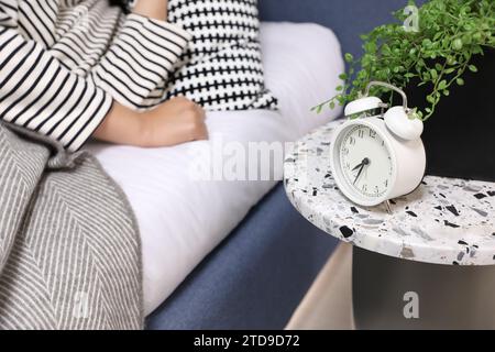 A woman lying in bed and an alarm clock on the bedside table Stock Photo