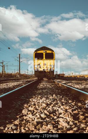 Low angle point of view of a goods rail locomotive approaching on railway tracks and sleepers with copy space Stock Photo