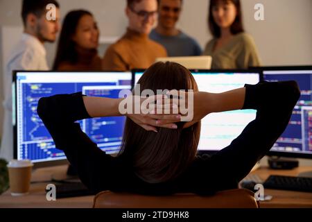 Female programmer working with team at office in evening, back view Stock Photo