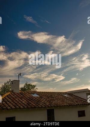 Beautiful cirrus clouds floating over a farm house in the eastern Andean mountains of central Colombia, at sunset. Stock Photo