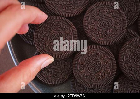 Tambov, Russian Federation - November 08, 2023 Woman taking Oreo cookie from a gray plate full of Oreo cookies Stock Photo