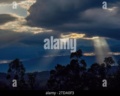 Some sun beams come trough dense clouds, in an overcast sunset over the eastern Andean mountains of central Colombia. Stock Photo