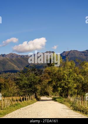 A gravel rural road flanked by the barbed wired fences of farmlands, in a clear afternoon, in the eastern Andean mountains of central Colombia. Stock Photo