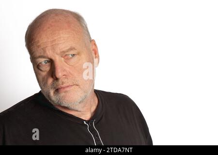 Middle-aged White Man in Black Shirt Looking Suspiciously Right on White Background Stock Photo