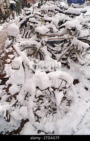Bicycles covered in snow in Amsterdam city centre Singel canal in winter Stock Photo
