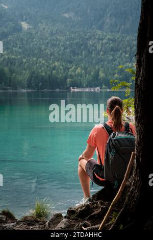 View from the shore of Lake Eibsee with a seated hiker in the foreground in Germany. Stock Photo