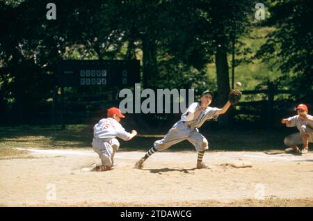 KINGS POINT, NY - 1960'S:  General view of a child sliding back to the base as the first baseman tries to catch the ball during a game between two teams from Kings Point Little League circa 1960's in Kings Point, New York.  (Photo by Hy Peskin/Getty Images) Stock Photo