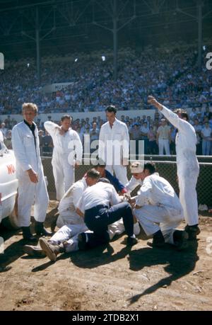 SACRAMENTO, CA - AUGUST, 1958: A group of men tend to the driver after his car flipped and crashed during a car show at the Sacramento State Fair circa August, 1958 in Sacramento, California. (Photo by Hy Peskin) Stock Photo