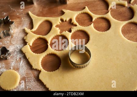 Cutting out circle shapes from rolled out dough to prepare homemade Linzer Christmas cookies Stock Photo