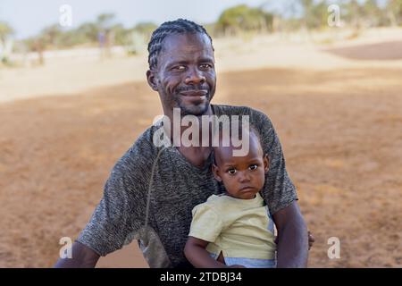 village young african father with child, standing in the yard in a sunny day , man with a dreadlocks hairstyle Stock Photo