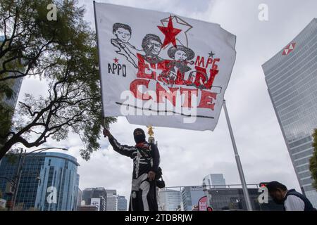 Mexico City, Mexico. 15th Dec, 2023. December 15, 2023 Mexico City, Mexico. A hooded person waves a flag, during a demonstration of the the National Coordinator of Education Workers in Mexico at Reforma Avenue to demand improvements to the education system and better salaries within the framework of the 44th anniversary of their union group. on December 15, 2023 in Mexico City, Mexico. (Photo by Alex Dalton/ Eyepix Group/Sipa USA) Credit: Sipa USA/Alamy Live News Stock Photo