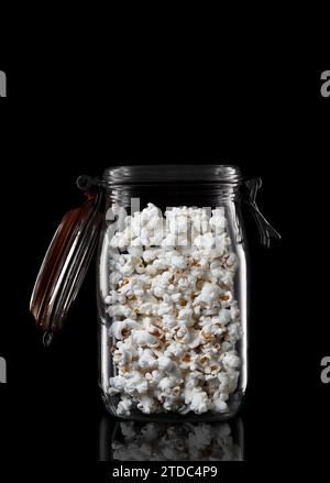 A glass storage or canning jar filled with popcorn isolated on black with reflection, with lid open. Stock Photo