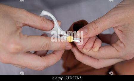 Mom cuts her newborn son's fingernails with small children's scissors. Stock Photo