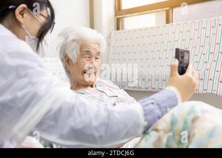 A grandmother and her granddaughter are holding a smartphone together and making a video call Stock Photo