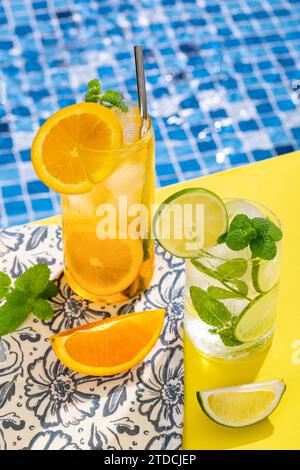 Orange juice, cocktail, screwdriver and mojito on tiled swimming pool background Stock Photo