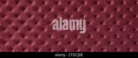 Texture of dark red leather background with capitone pattern, macro. Wine textile of retro Chesterfield style. Vintage ruby fabric backdrop. Stock Photo