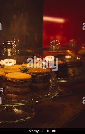 Glass pot with macarons and cakes. Cake shop interior. Cheesecake and macaroons in showcase. Pastry shop with dessert in glass. Bakery cafe. Stock Photo