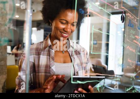 Success black happy business woman using tablet computer and working. Designer manager in her office Stock Photo