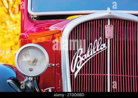 uzhgorod, ukraine - 31 oct 2021: front close-up of a red fiat 508 balilla oldtimer with chrome logo on the grille. sunny outdoor in autumn park Stock Photo