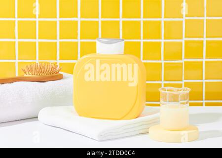 A blank yellow shower gel bottle rests on a white table against a checkered tile background. Elevate advertising with this perfect setting to showcase Stock Photo