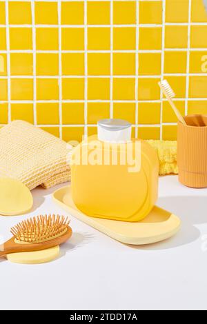 A label-free yellow shower gel bottle stands on a white table against a checkered tile backdrop. Perfectly showcase shower gel in this ideal advertise Stock Photo