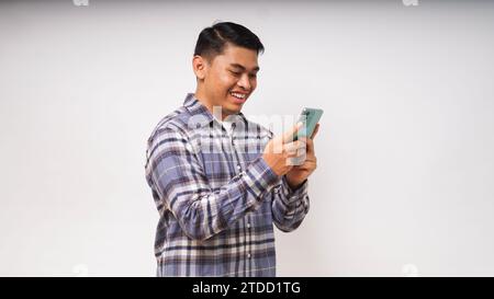 Young Asian man holding mobile phone showing enthusiastic expression Stock Photo