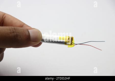 Lithium polymer battery of small size mostly used to power electronic gadgets like the wearable bluetooth earphones held in the hand Stock Photo