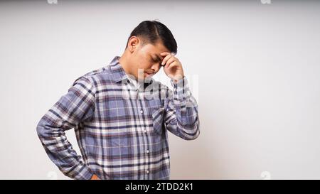 Asian young man showing in pain expression while touching his head Stock Photo