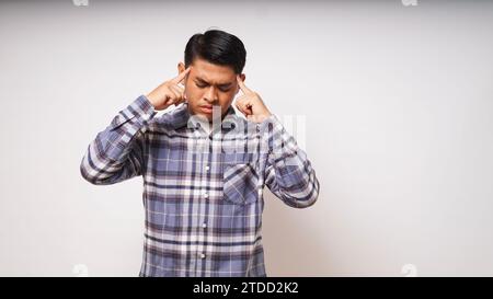 Asian young man showing in pain expression while touching his head Stock Photo