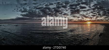 Awesome panoramic 180 degrees of rough sea at sunset, a dramatic sky with amazing light and cloudscape of mammatus clouds between sunbeam reflections Stock Photo